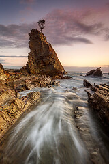 Image showing Water flowing fast through narrow chasm beside seastack woth sol