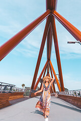 Image showing Carefree woman walking vicaciously across a modern bridge across