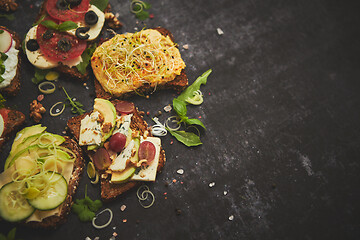 Image showing Variety of healthy fresh sandwiches with different vegetables, herbs and ingredients on dark table