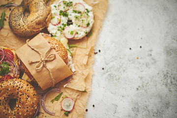 Image showing Bagels with ham, cream cheese, hummus, radish wrapped in brown baking paper ready for take away