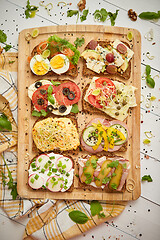 Image showing Colorful, different kinds sandwiches served on wooden chopping board. Vegetable toppings