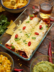 Image showing Vegetable Burritos served in glass heatproof dish. With salsa, guacamole, nachos and ingredients