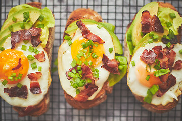 Image showing Breakfast concept. Tasty delicious homemade toasts with fried egg, bacon, avocado, lettuce and chive