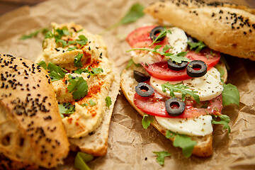 Image showing Two delicious sandwiches with hummus, tomato, mozarella cheese, herbs and olives