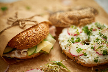 Image showing Bagels with ham, cream cheese, hummus, radish wrapped in brown baking paper ready for take away