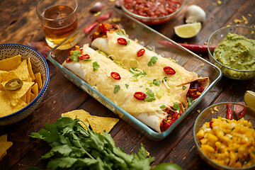 Image showing Vegetable Burritos served in glass heatproof dish. With salsa, guacamole, nachos and ingredients