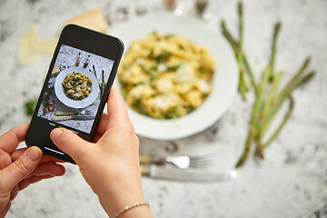 Image showing Woman making a photo with a smarpthone of homemade tagliatelle pasta with creamy ricotta