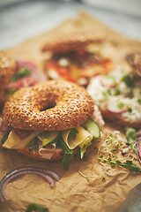 Image showing Bagel sandwiches with various toppings, salmon, cottage cheese, hummus, ham, radish and fresh herbs