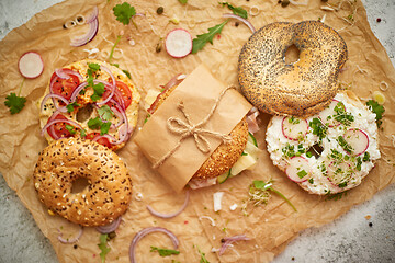 Image showing Bagels with ham, cream cheese, hummus, radish wrapped in brown baking paper ready for take away