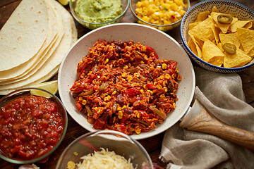 Image showing Mexican food concept. Vegetable burritos. Served on pan. Tortilla guacamole, salsa, chilli and beans