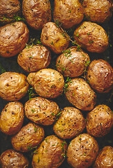 Image showing Oven baked whole potatoes with seasoning and herbs in metalic tr