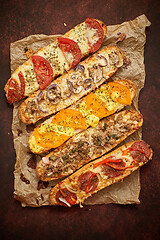 Image showing Assortment of various toppings baked sandwiches. With melted cheese, vegetables, tuna, olives spices