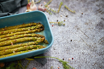 Image showing Roasted asparagus seasoned with salt, pepper, garlic and decorated with fresh herbs