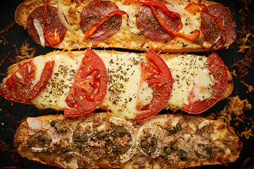 Image showing Long baguettes pizza sandwiches with tuna, mushrooms, tomatoes and cheese on a metal baking tray