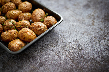 Image showing Homemade roasted whole potatoes in jackets. With butter, rosemary and thyme. Served in metallic dish