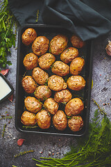 Image showing Tasty fresh homemade baked potatoes served on a metal tray. With various herbs, butter, garlic, salt