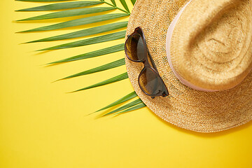 Image showing Straw hat, green palm leaf and sunglasses on yellow backdrop. Su