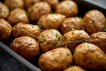 Image showing Close up on homemade roasted whole potatoes in jackets. With butter, rosemary and thyme.