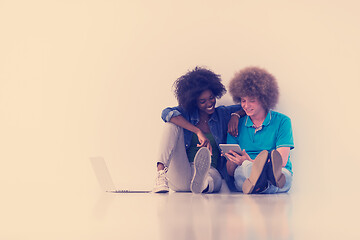 Image showing multiethnic couple sitting on the floor with a laptop and tablet