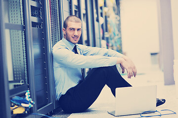 Image showing businessman with laptop in network server room