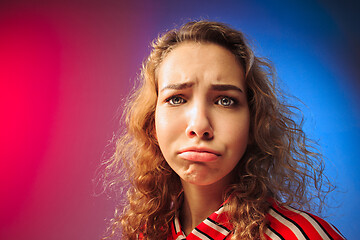 Image showing The serious sad woman standing and looking at camera against colorful background.