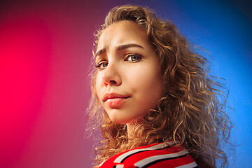 Image showing The serious sad woman standing and looking at camera against colorful background.