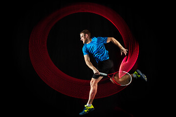 Image showing one caucasian man playing tennis player on black background