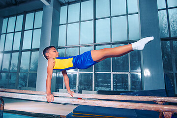 Image showing beautiful boy is engaged in sports gymnastics on a parallel bars