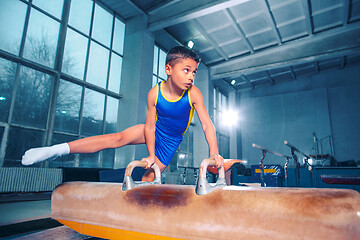 Image showing The sportsman performing difficult gymnastic exercise at gym.