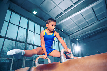 Image showing The sportsman performing difficult gymnastic exercise at gym.