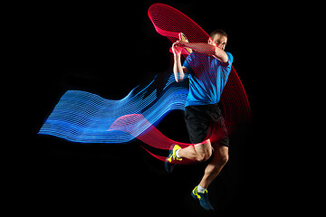 Image showing one caucasian man playing tennis player on black background