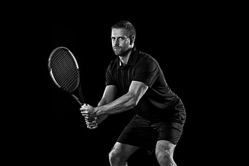 Image showing one caucasian man playing tennis player on black background