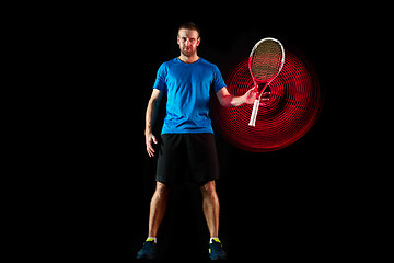 Image showing one caucasian man playing tennis player on black background