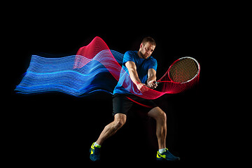 Image showing one caucasian man playing tennis player on black background