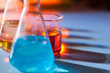 Image showing Illuminated laboratory flask filed with colorful chemical solutions with shadows on the table. Laboratory, science, chemistry... consept.