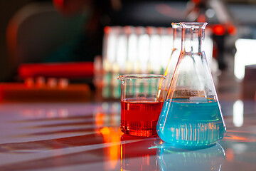 Image showing Illuminated laboratory flask filed with colorful chemical solutions with shadows on the table. Laboratory, science, chemistry... consept.