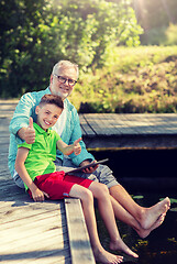 Image showing grandfather and boy with tablet pc on river berth