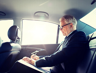 Image showing senior businessman with papers driving in car
