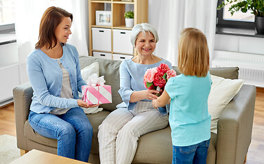 Image showing granddaughter giving flowers to grandmother