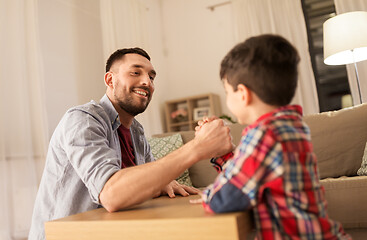 Image showing happy father and little son arm wrestling at home