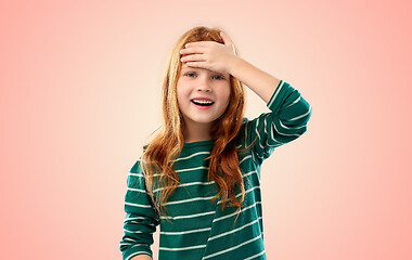 Image showing smiling red haired girl holding to her head