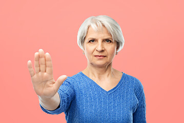 Image showing senior woman in blue sweater making stop gesture