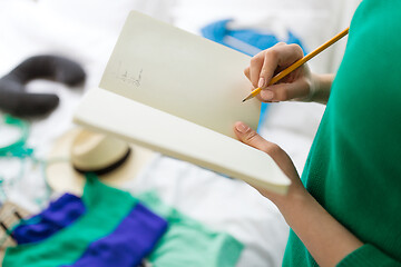 Image showing woman going on trip and making list in notebook