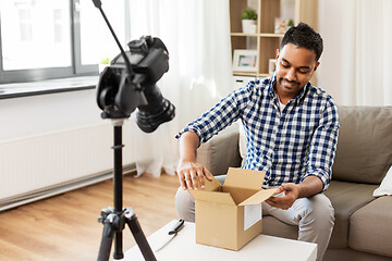 Image showing male video blogger opening parcel box at home