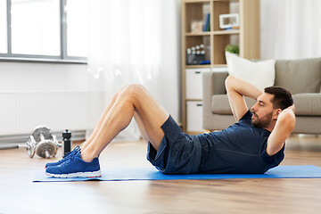 Image showing man making abdominal exercises at home