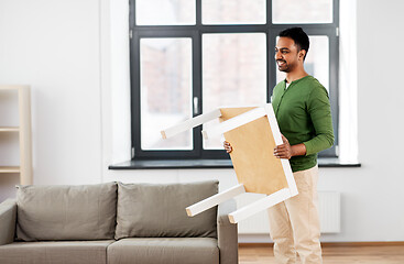 Image showing happy indian man holding coffee table at home