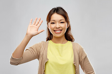 Image showing happy asian woman waving hand