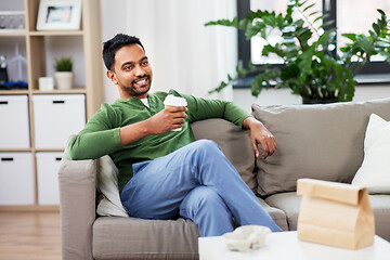 Image showing happy indian man drinking takeaway coffee at home