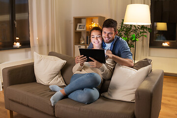 Image showing happy couple using tablet pc at home in evening