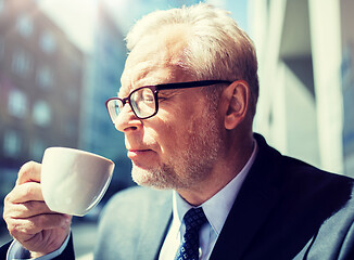 Image showing senior businessman drinking coffee on city street